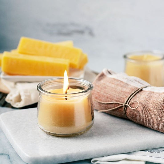 lit beeswax candle sitting on bench top, front side