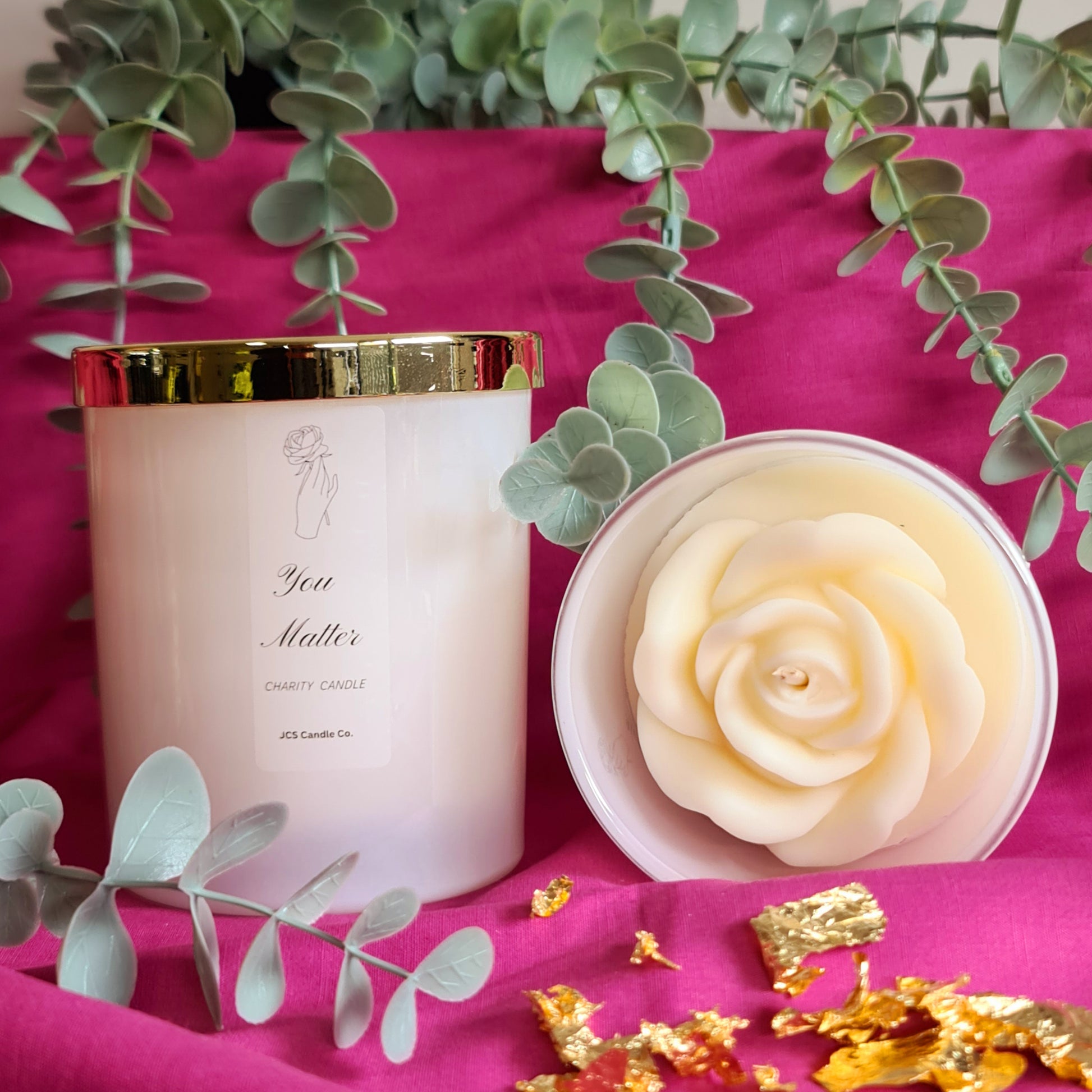 you matter scented candle, one jar laying down, showing the rose top, one jar standing with gold lid